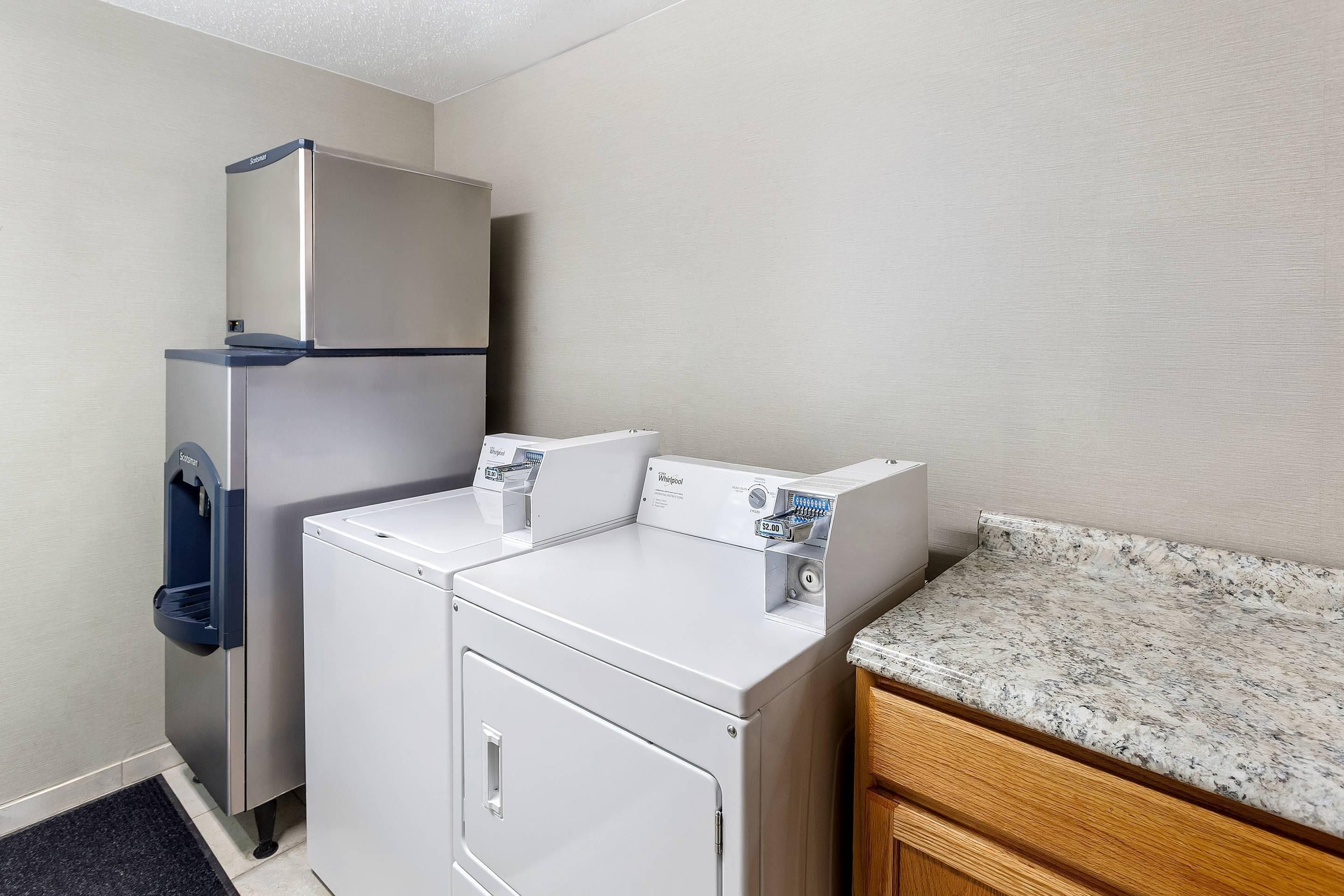 A laundry room with a refrigerator, a washing machine, and a dryer.