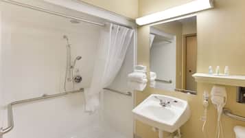 A bathroom with a shower, a sink, a mirror, and a towel rack.