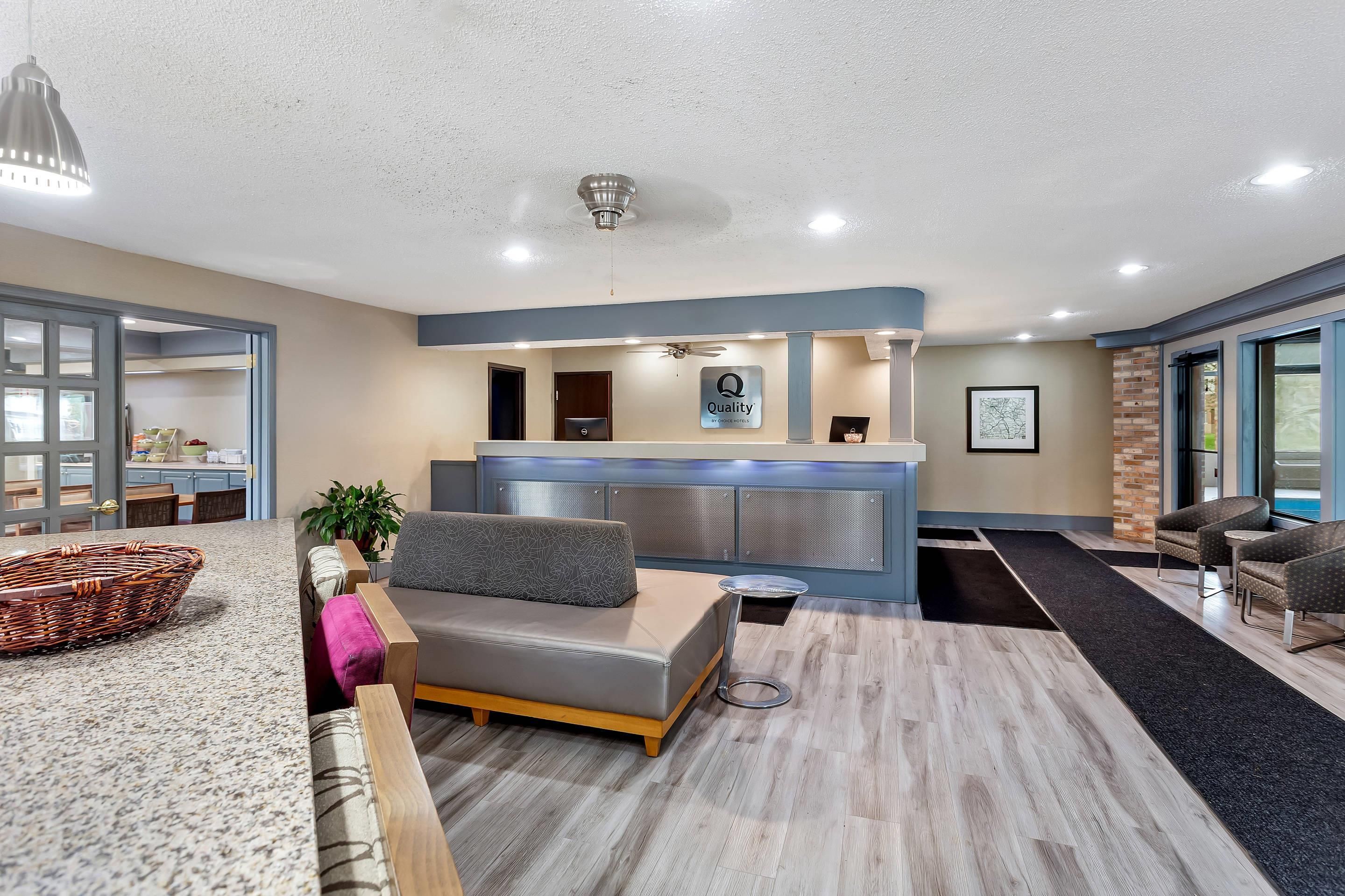 A hotel lobby with a reception desk, seating area, and a view of the outside.