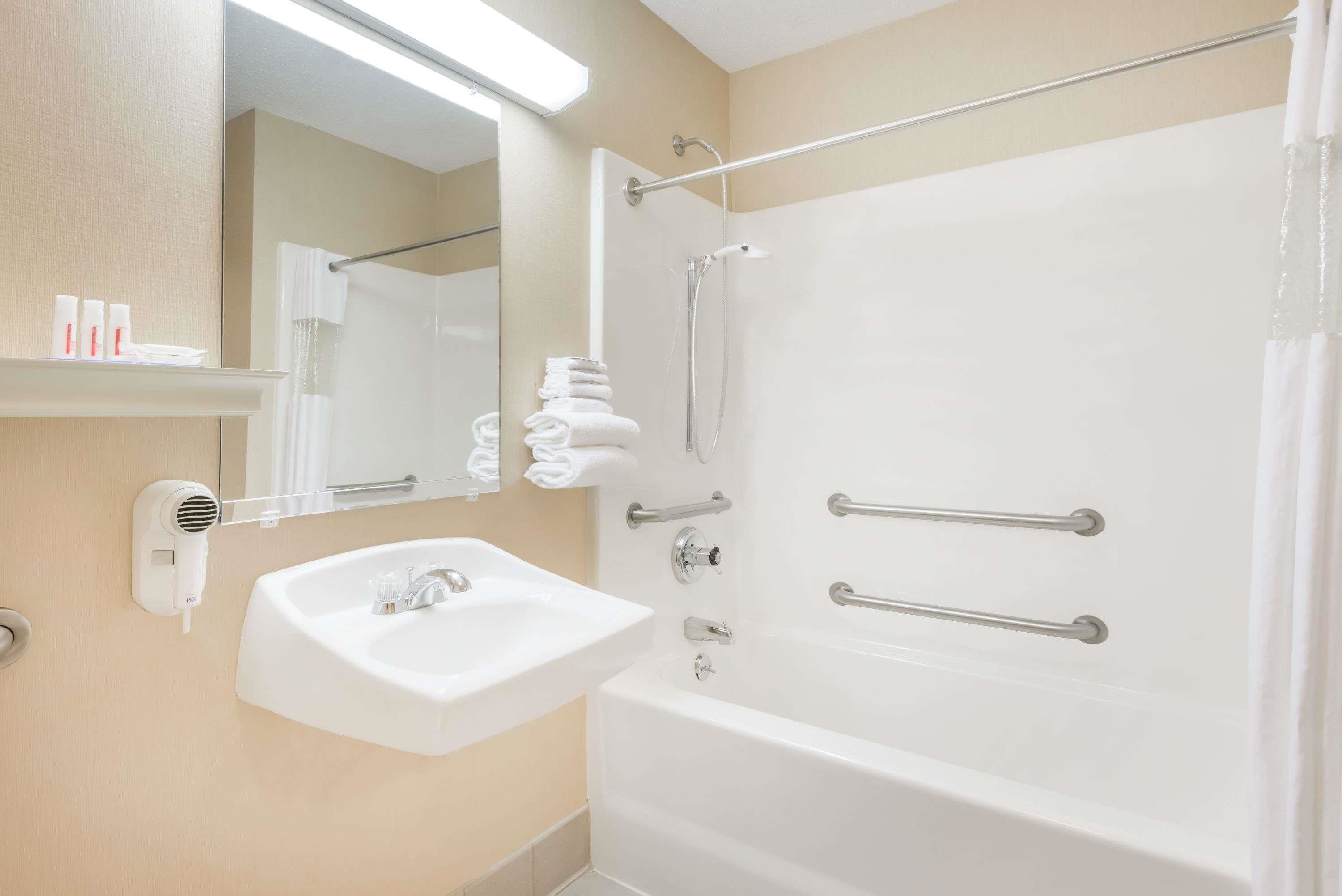 A bathroom with a white sink, a mirror, a shower with a glass door, and a towel rack.