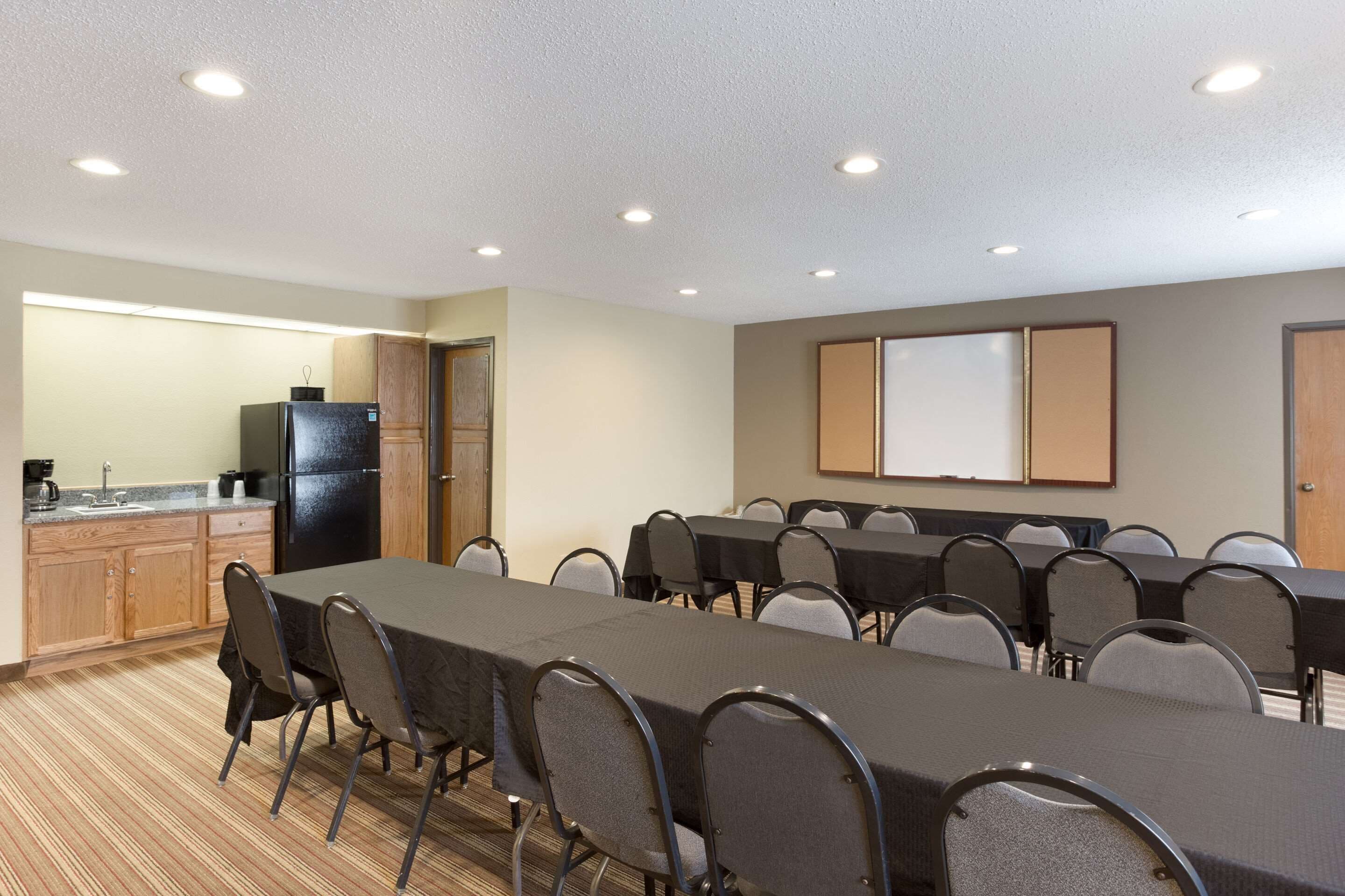 Une salle de conférence équipée d’une longue table, de chaises, d’un réfrigérateur, d’une machine à café et d’un tableau blanc.