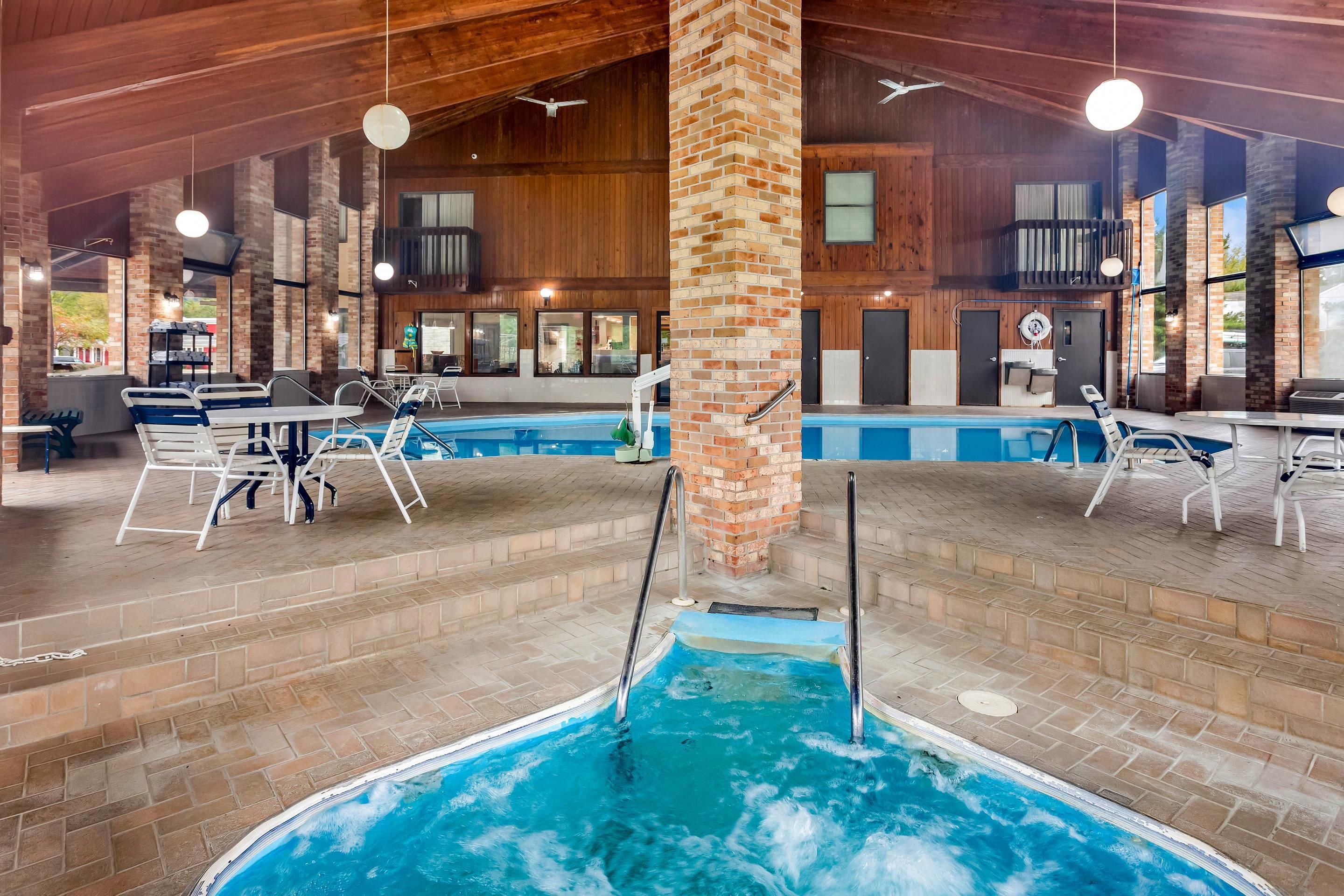 An indoor swimming pool with multiple lanes, surrounded by lounge chairs and tables, and wooden paneling on the walls.