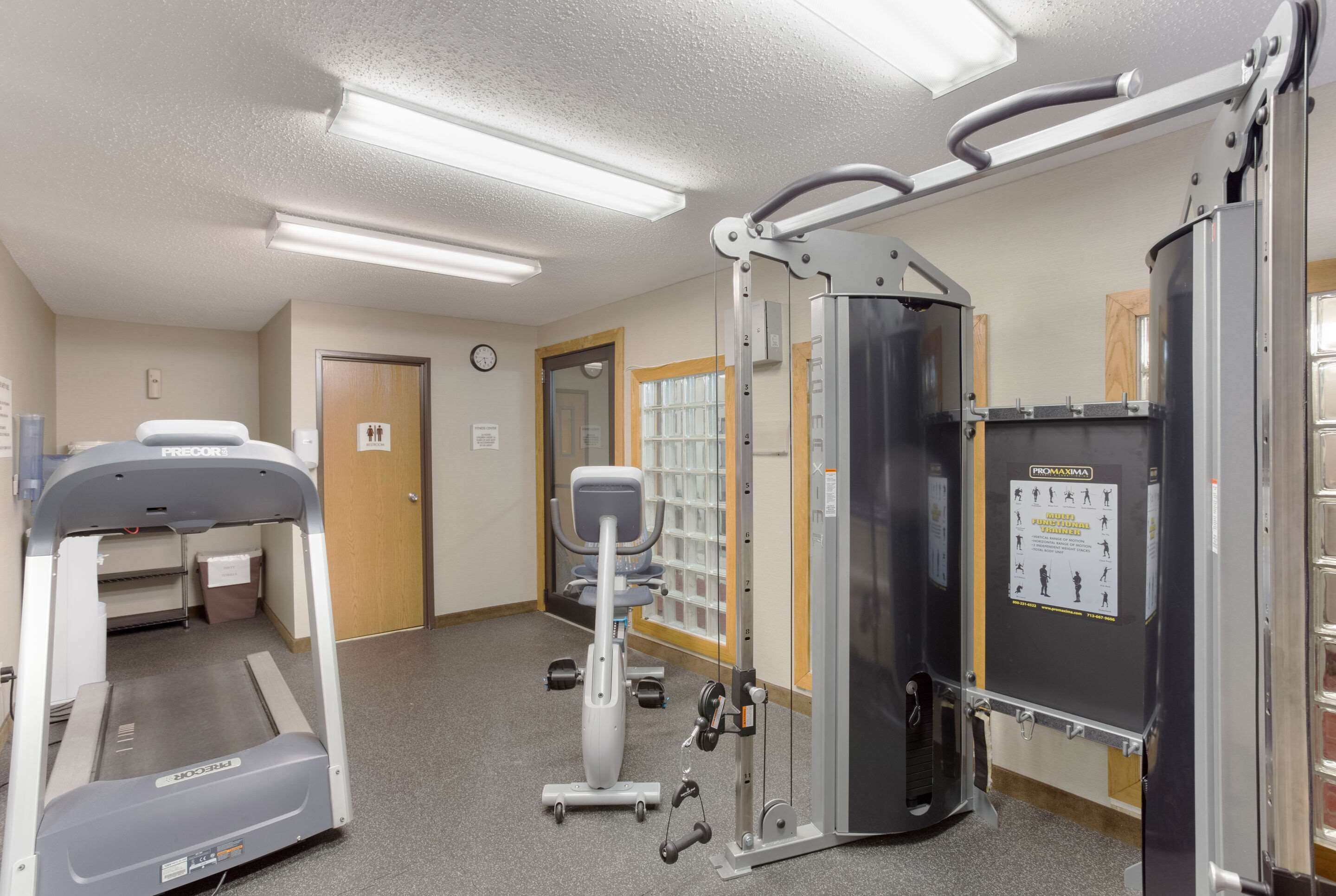 Ein Fitnessstudio mit Laufband, Crosstrainer und Krafttrainingsgeräten.