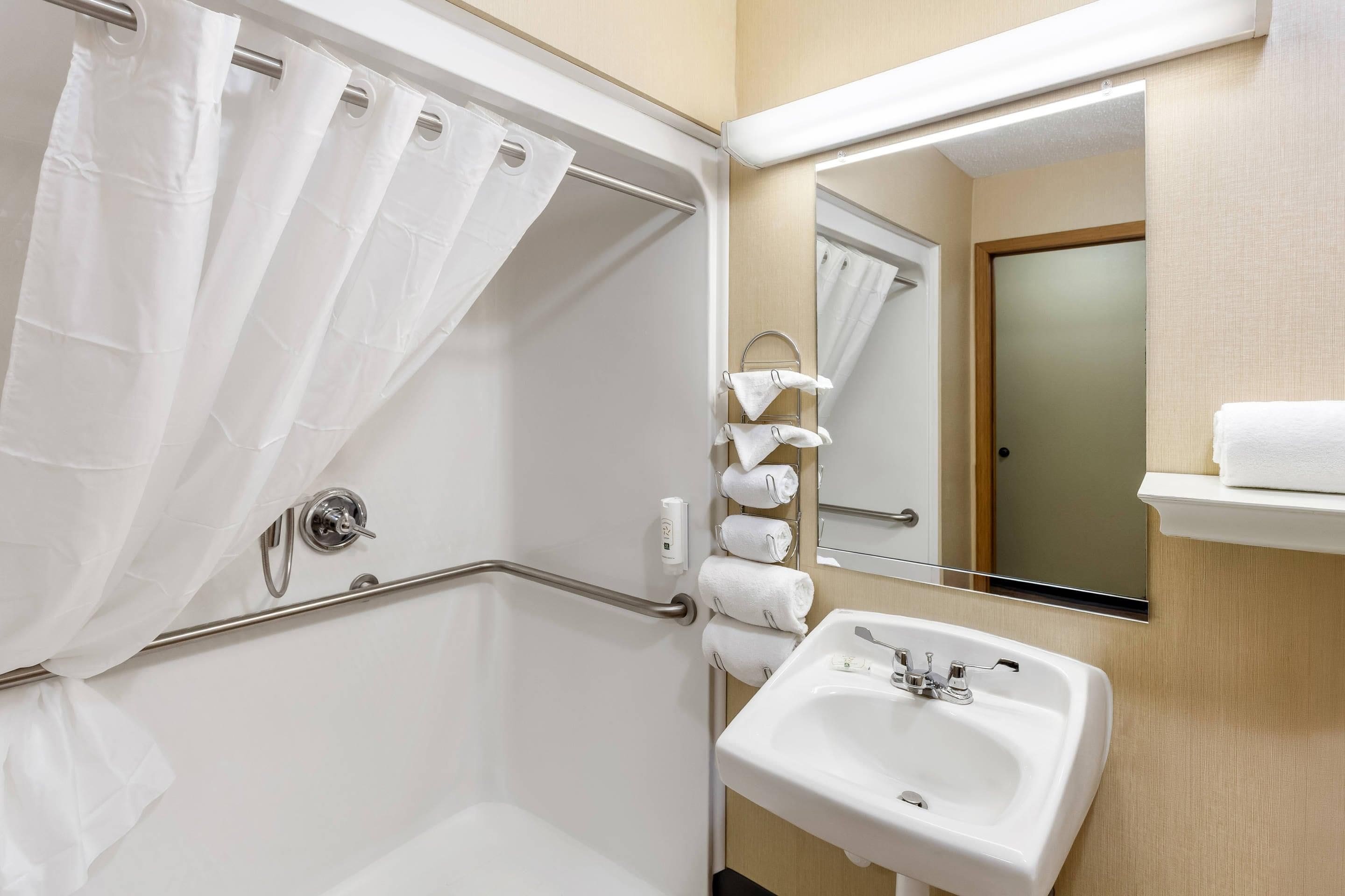 A bathroom with a shower, a sink, a towel rack, and a mirror.