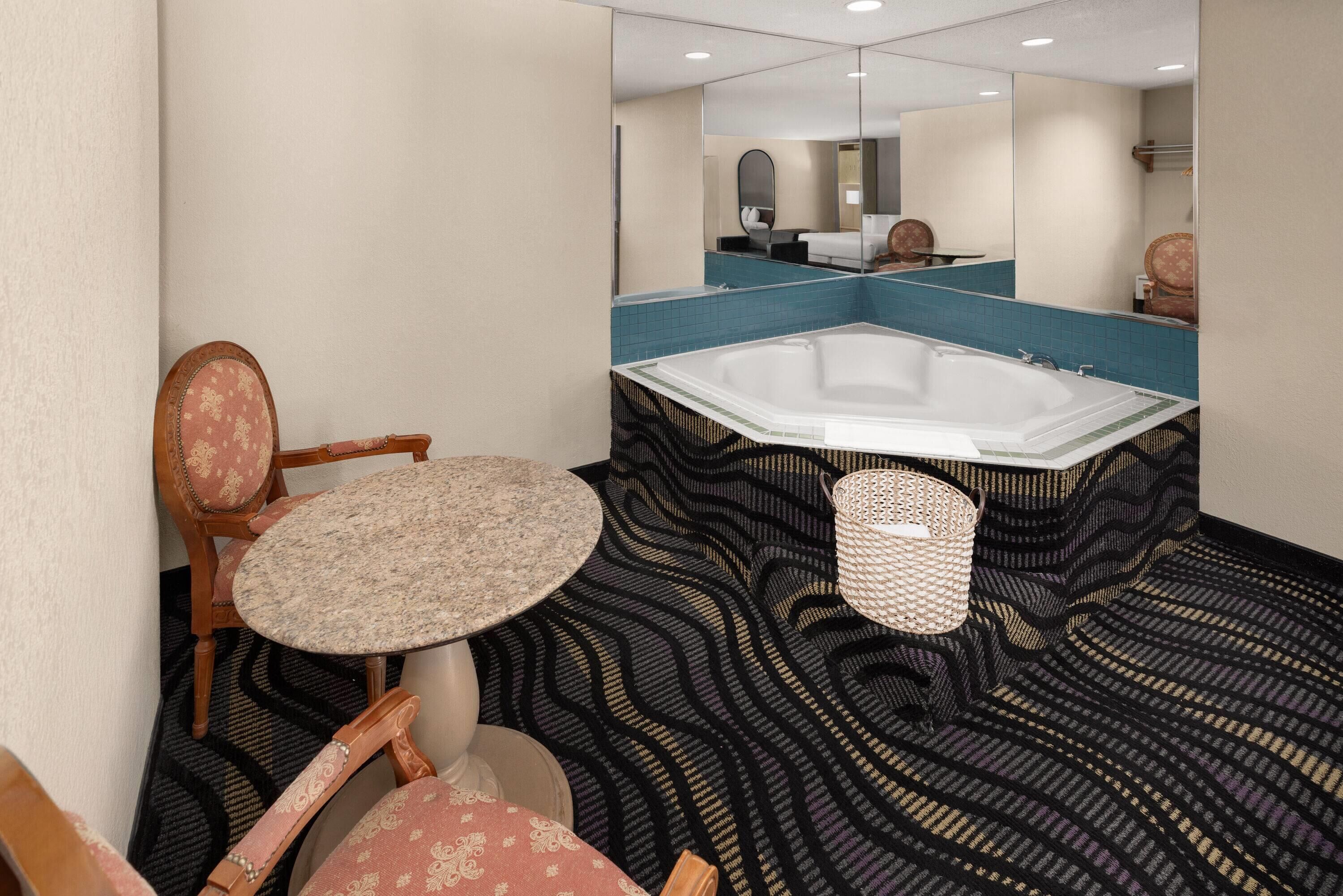 Un baño con una bañera grande, una mesa redonda y una silla.
