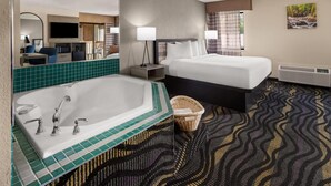 Camera d'albergo con una grande vasca da bagno, due letti, una televisione a schermo piatto, una scrivania con una sedia e un grande specchio.
