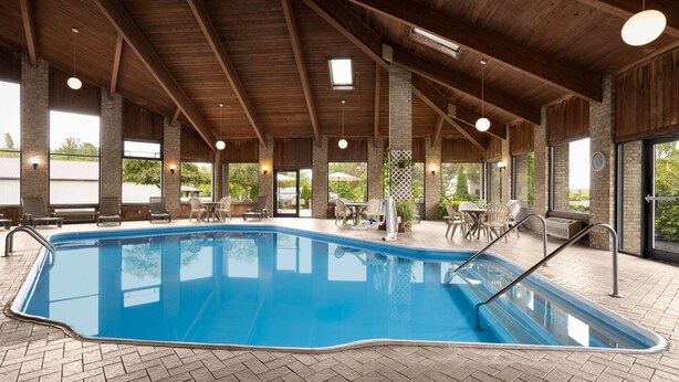 Una piscina con pavimento in piastrelle a mosaico a spina di pesce, travi in legno e ampie finestre.