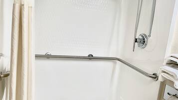 A bathtub with a grab bar, a showerhead, and a towel rack.
