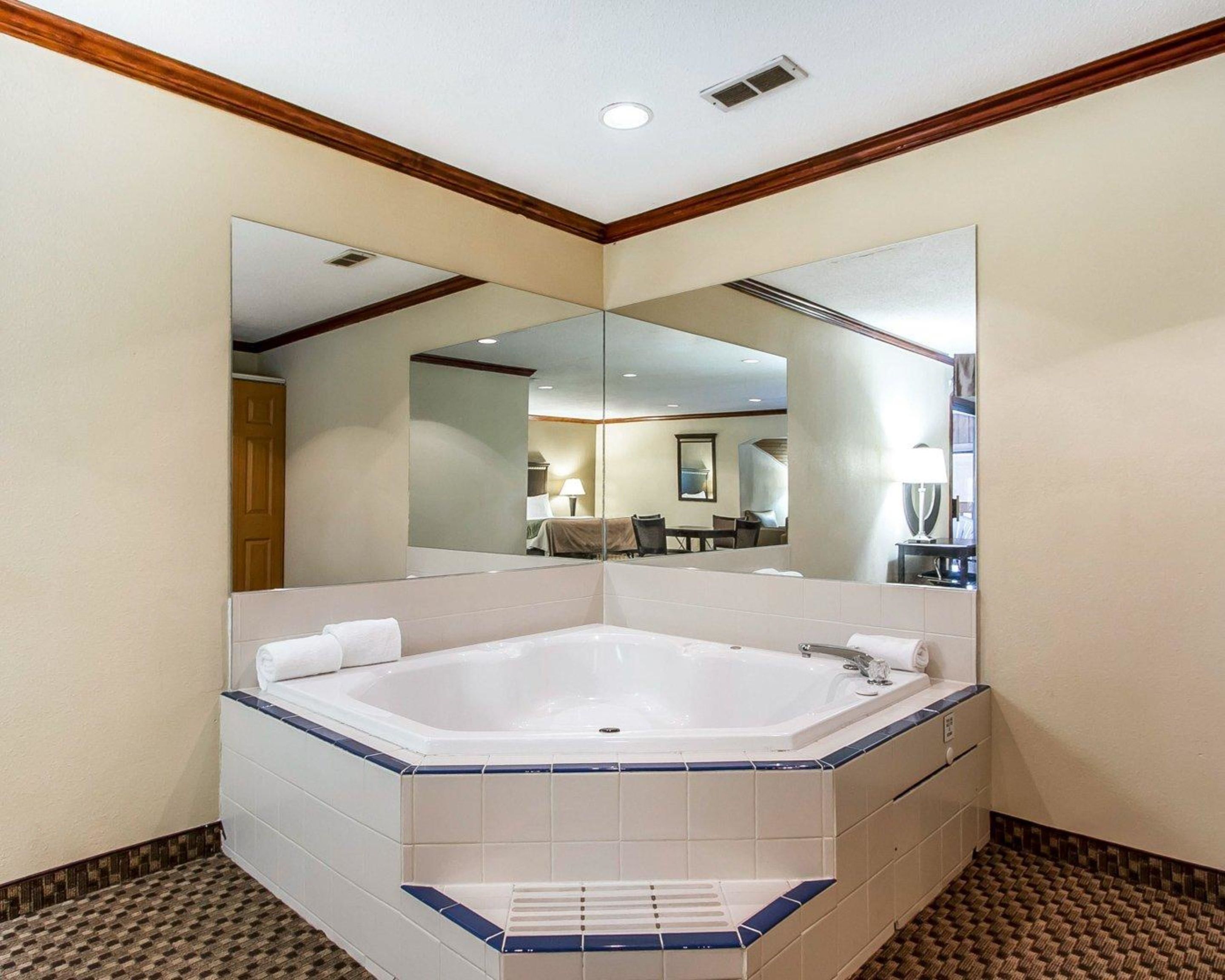 A modern bathroom with a large bathtub, a mirror, and a patterned floor.
