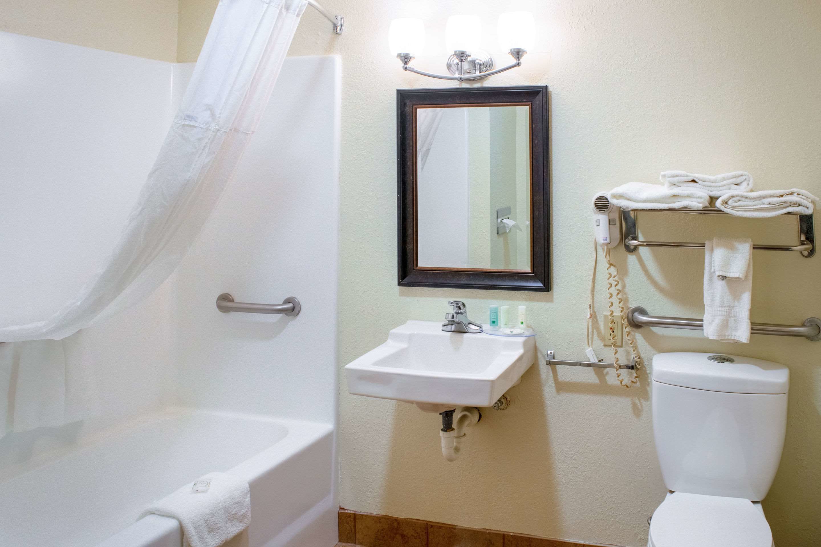 Un baño con bañera, lavabo, espejo e inodoro.