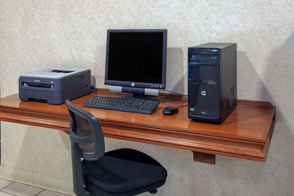 Un bureau en bois avec un ordinateur de bureau, un écran, une imprimante, un clavier, une souris et une chaise.