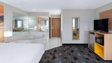 Hotelkamer met een groot bed, een aparte badkamer met bad, een televisie en een kleine koelkast.