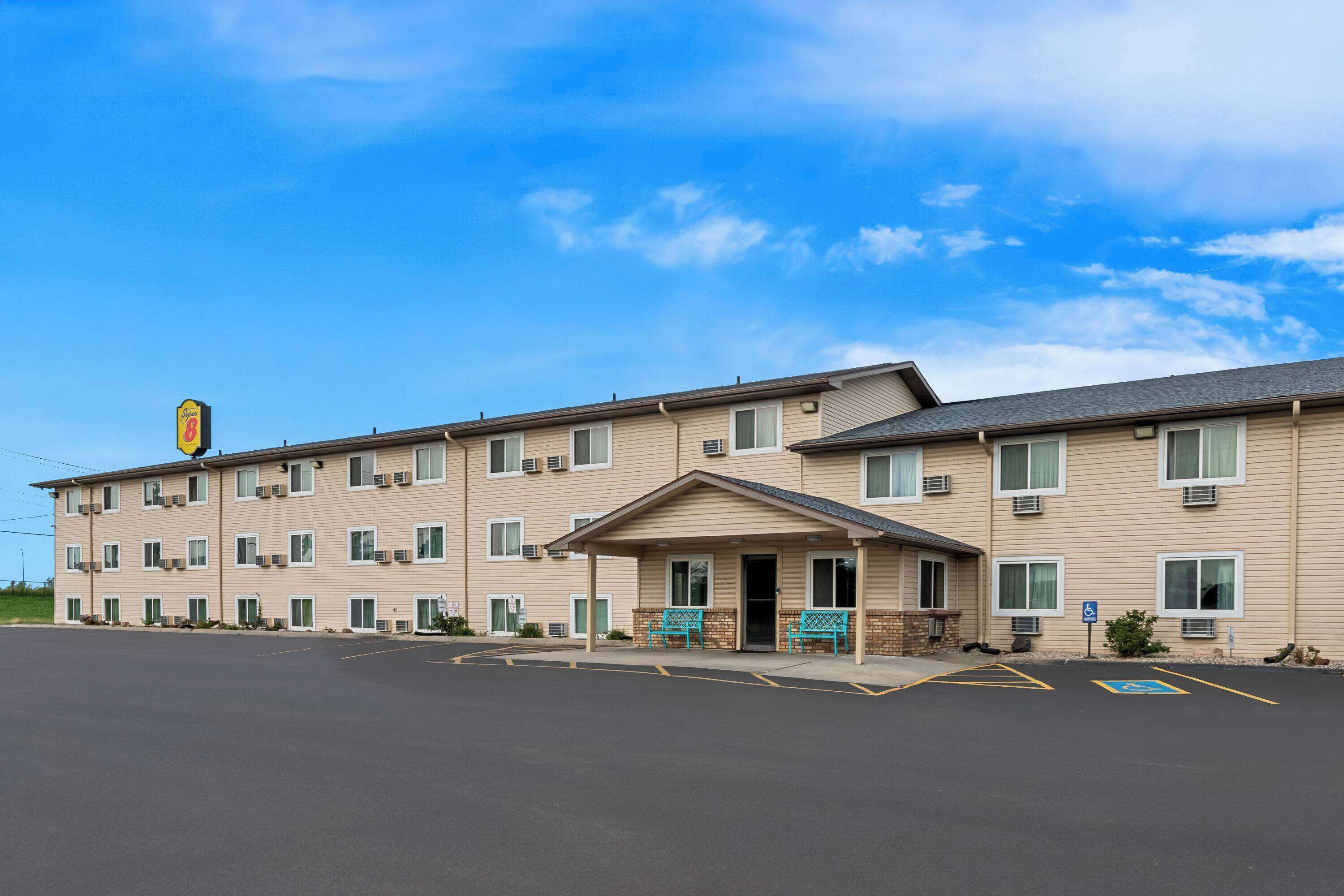 A motel with a central entrance, multiple windows, and a parking lot.