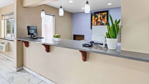 A reception desk with a flat-screen TV, a plant, and a coffee machine. - Super 8 by Wyndham Council Bluffs IA Omaha NE Area (Council Bluffs)