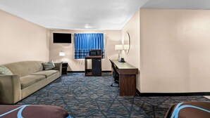 A hotel room with a sofa, a desk, a microwave, a lamp, and a TV. - Super 8 by Wyndham Council Bluffs IA Omaha NE Area (Council Bluffs)
