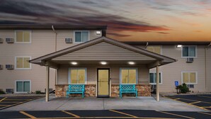 A hotel entrance with a covered porch, two blue benches, and a parking lot. - Super 8 by Wyndham Council Bluffs IA Omaha NE Area (Council Bluffs)