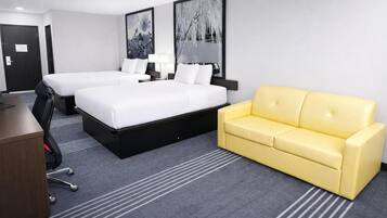 A hotel room with two beds, a yellow sofa, a desk, and a chair.
