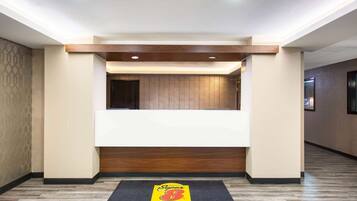 A hotel reception area with a reception desk, a wooden accent wall, and a reception mat with the hotel's logo.
