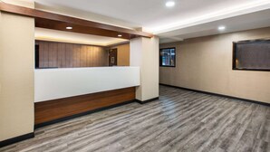 Un área de recepción con un mostrador de madera, una pantalla montada en la pared y un piso estampado.