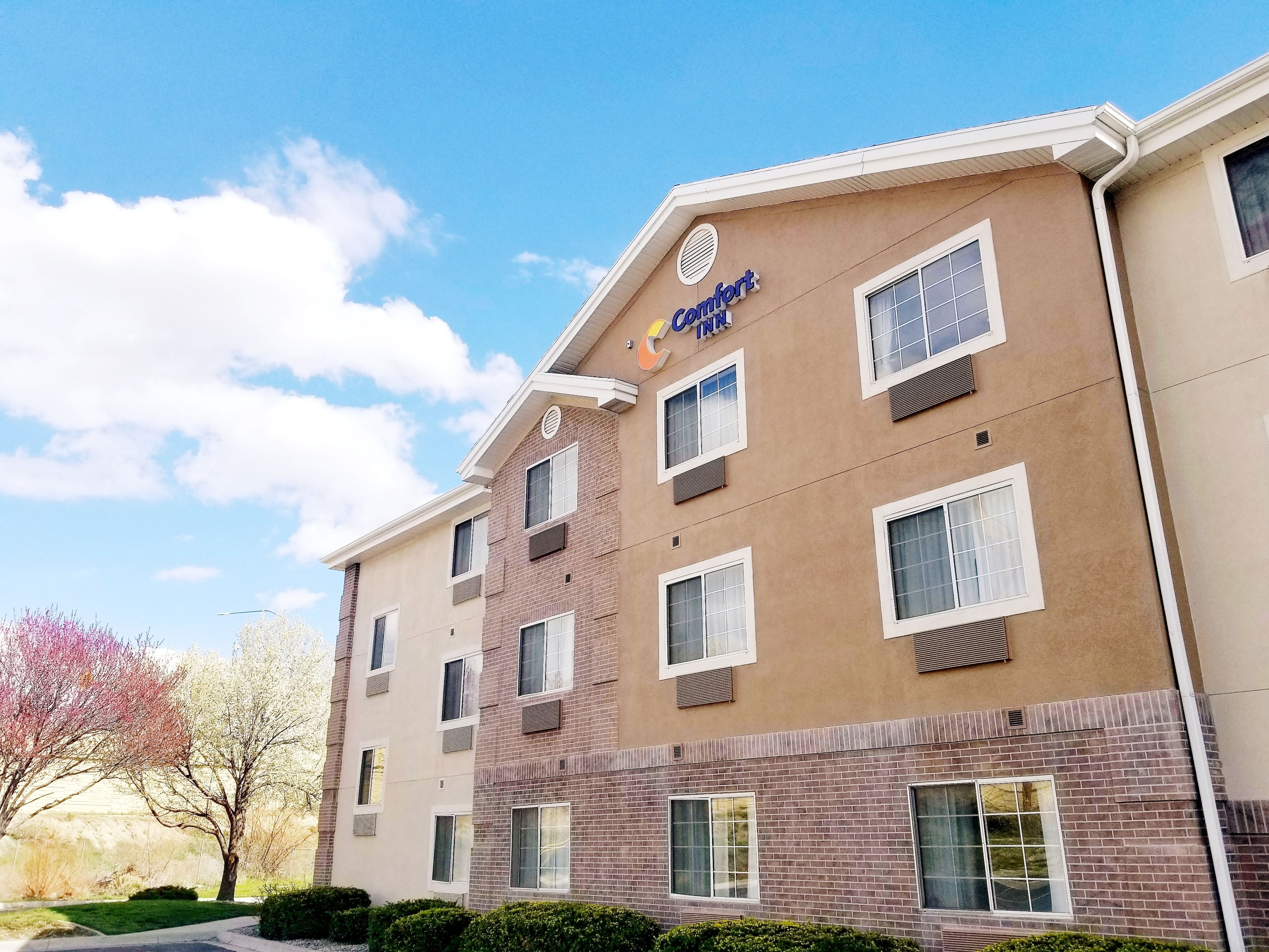 Un hotel de varios pisos con fachada color beige, múltiples ventanas y un letrero que dice 'Comfort Inn'.