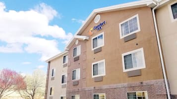 Un hotel de varios pisos con fachada color beige, múltiples ventanas y un letrero que dice 'Comfort Inn'.
