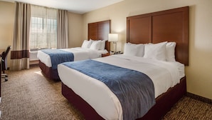 A hotel room with two beds, a desk, and a chair.