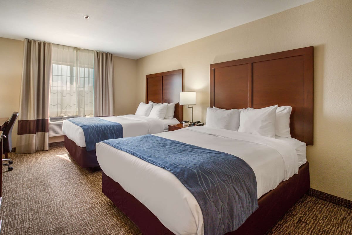 Ein Hotelzimmer mit zwei Betten, einem Schreibtisch und einem Sessel.