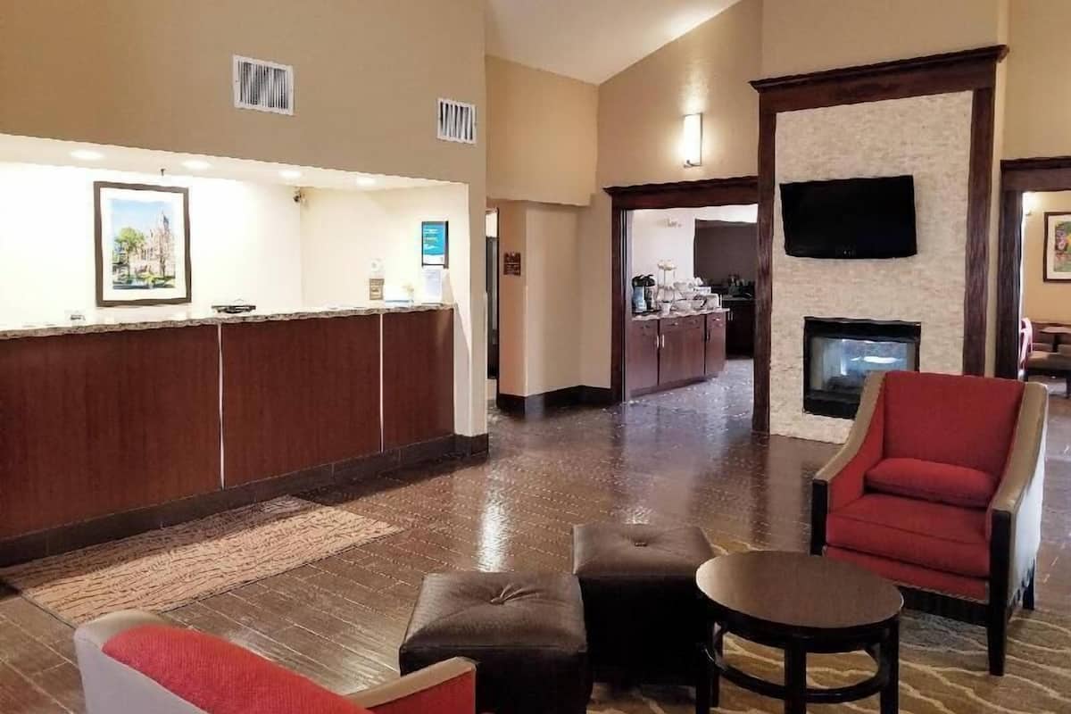Eine Hotelhalle mit einer Rezeption, einem Kamin, einer Sitzecke und einem an der Wand montierten Fernseher.
