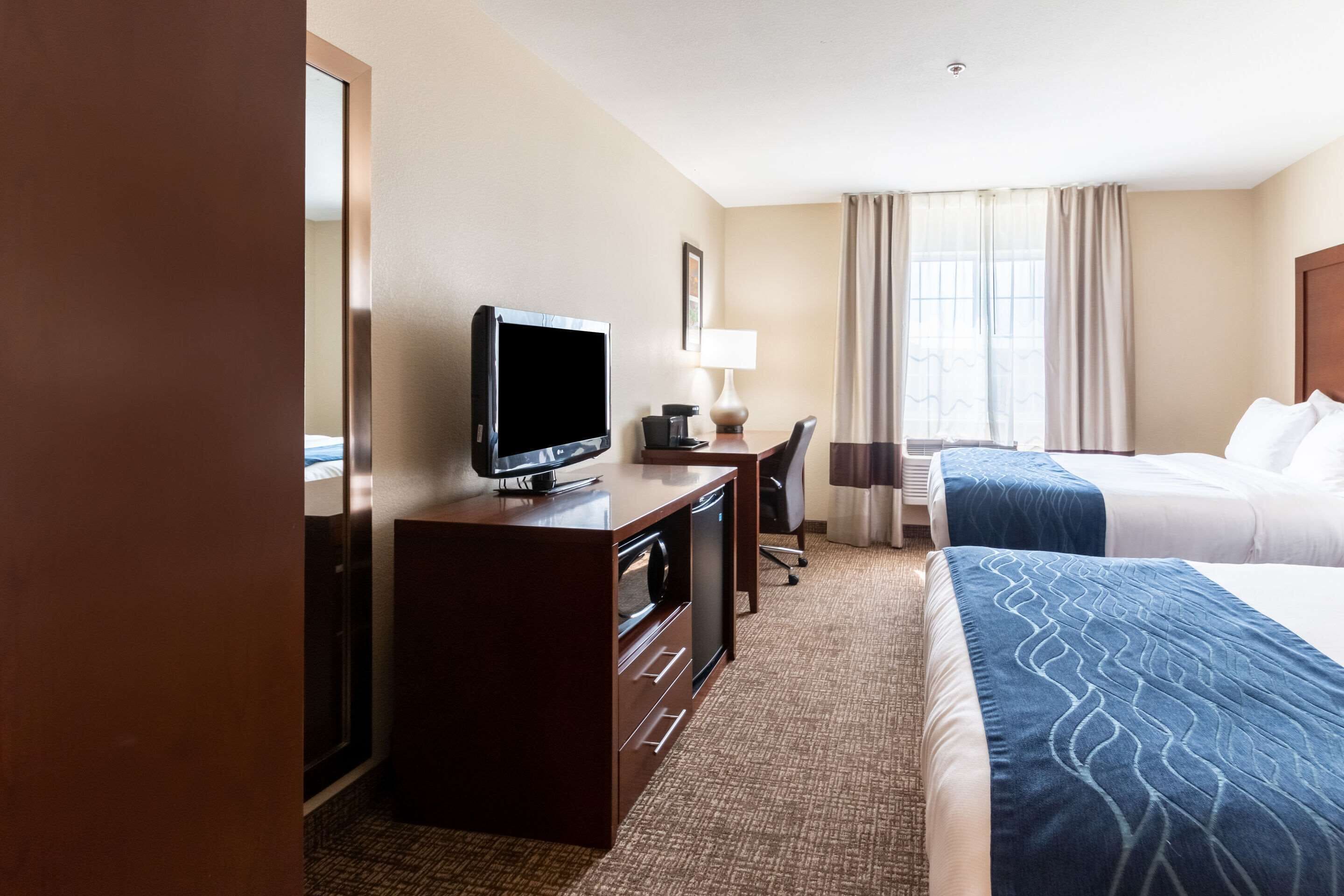 Une chambre d’hôtel comprenant un lit, un bureau avec une télévision, une chaise et une lampe.