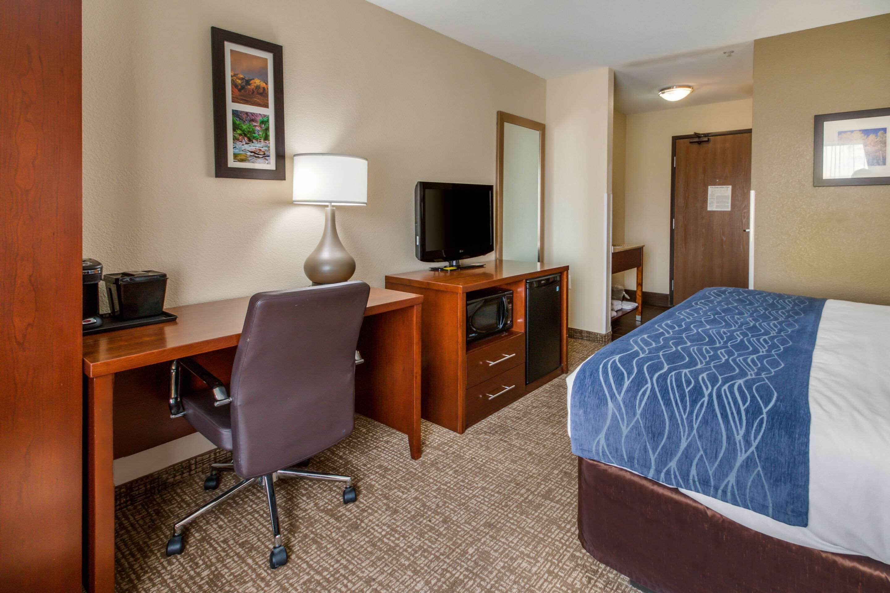 Une chambre d’hôtel équipée d’un lit, d’un bureau, d’une chaise, d’une télévision et d’un miroir.