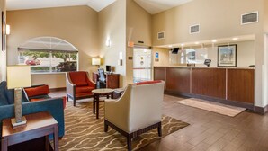 A lobby with a reception desk, seating area, and a view of the parking lot.