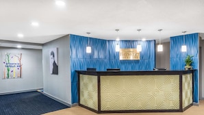 A reception area with a blue curtain backdrop, a reception desk, and a sign that reads "Baymont Inn & Suites."