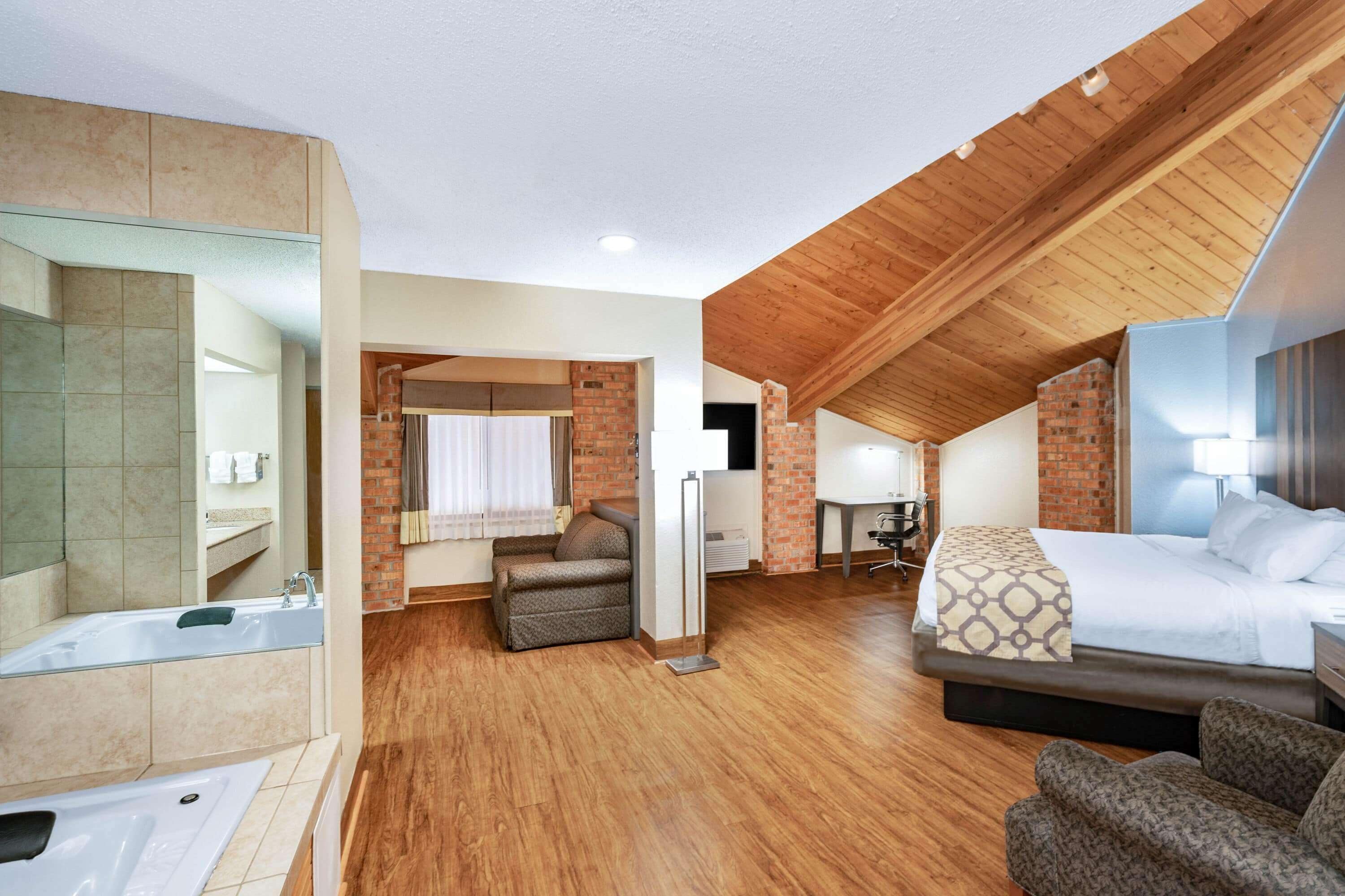A spacious room with a large bed, a sitting area, and a separate bathroom with a bathtub.