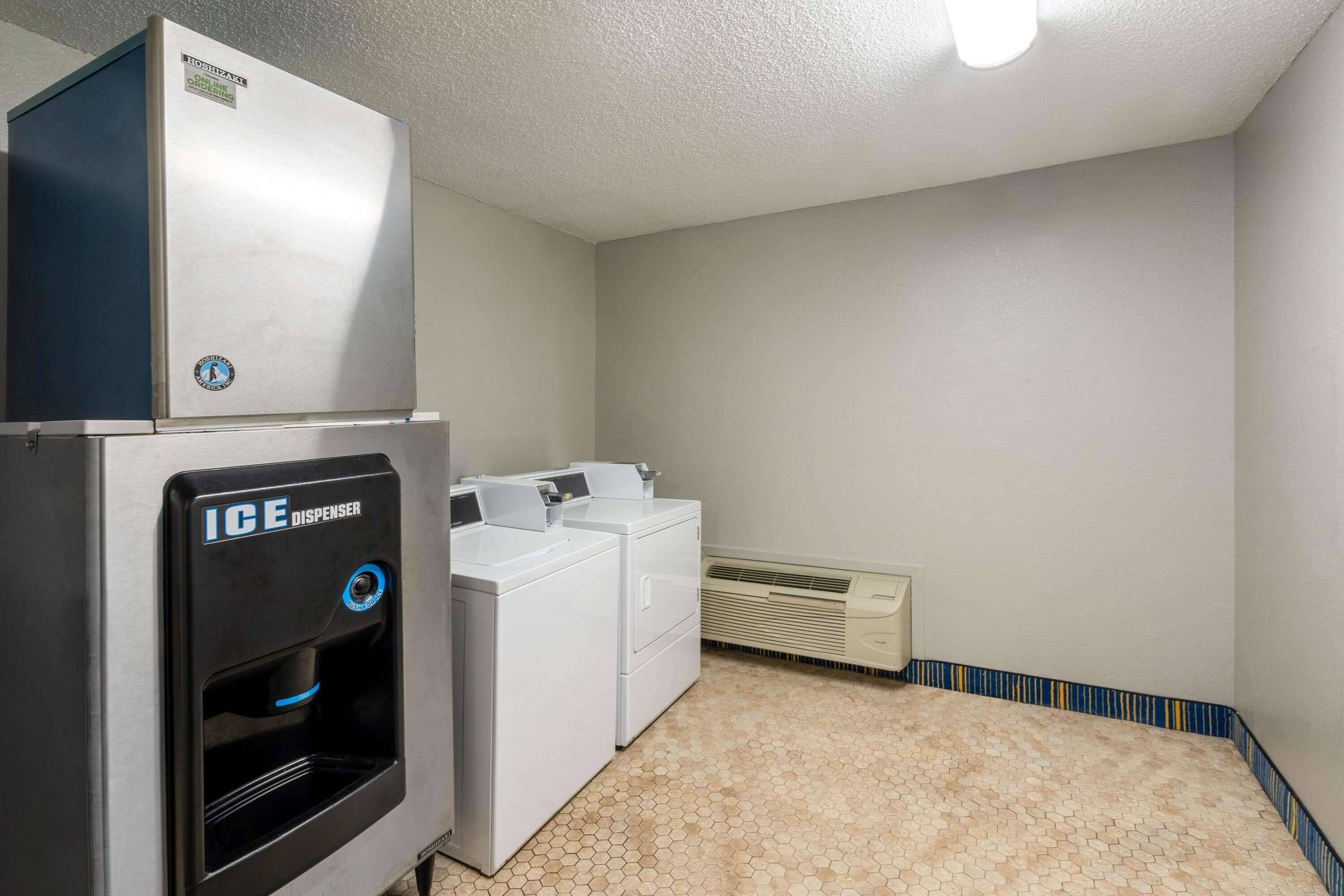 A laundry room with an ice dispenser, a washing machine, and a dryer.