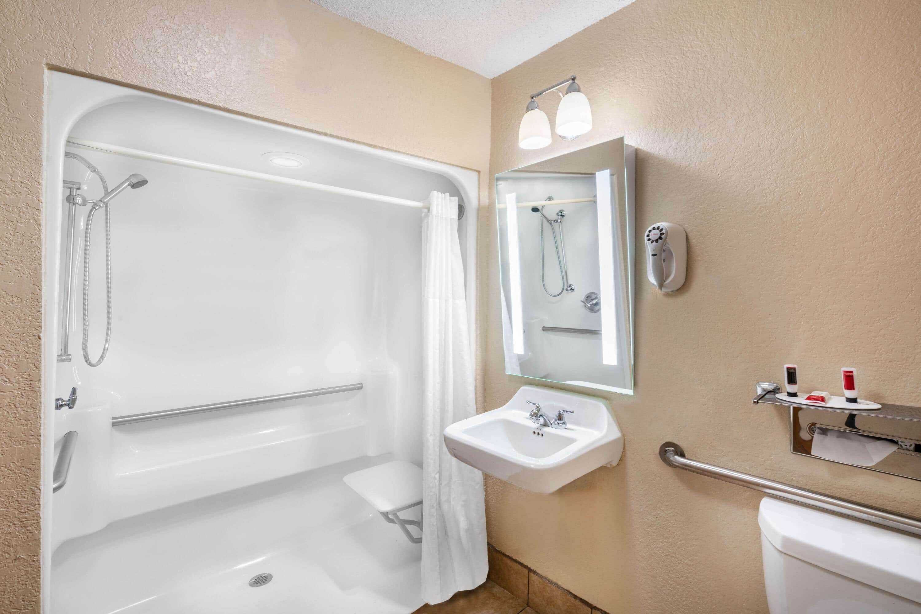 A bathroom with a bathtub, a sink, a toilet, and a mirror.