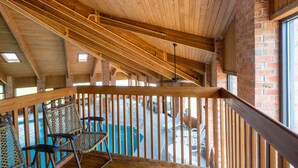 A wooden deck with chairs overlooking a pool area.