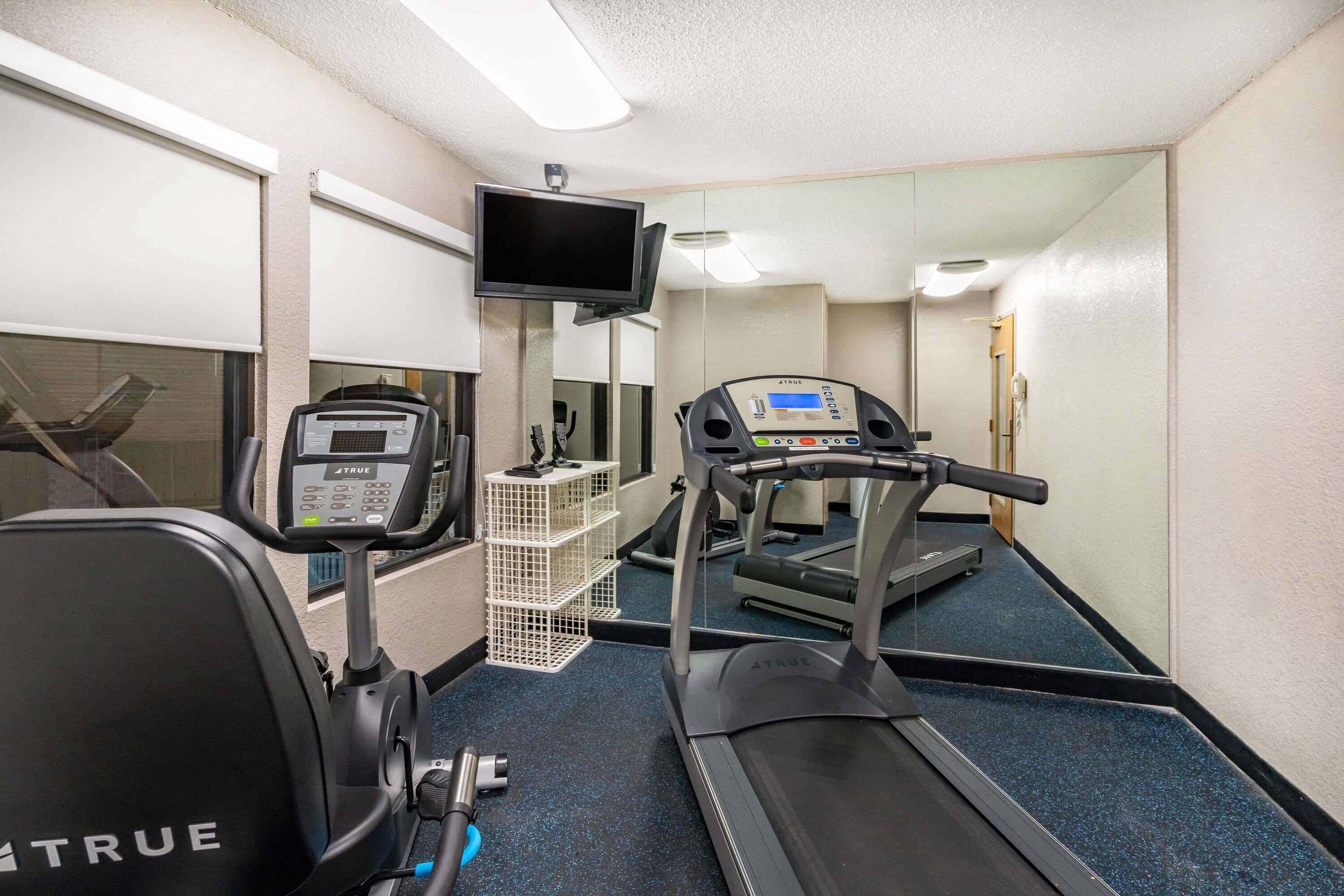 A gym with exercise equipment including a treadmill, stationary bike, and weight machine.