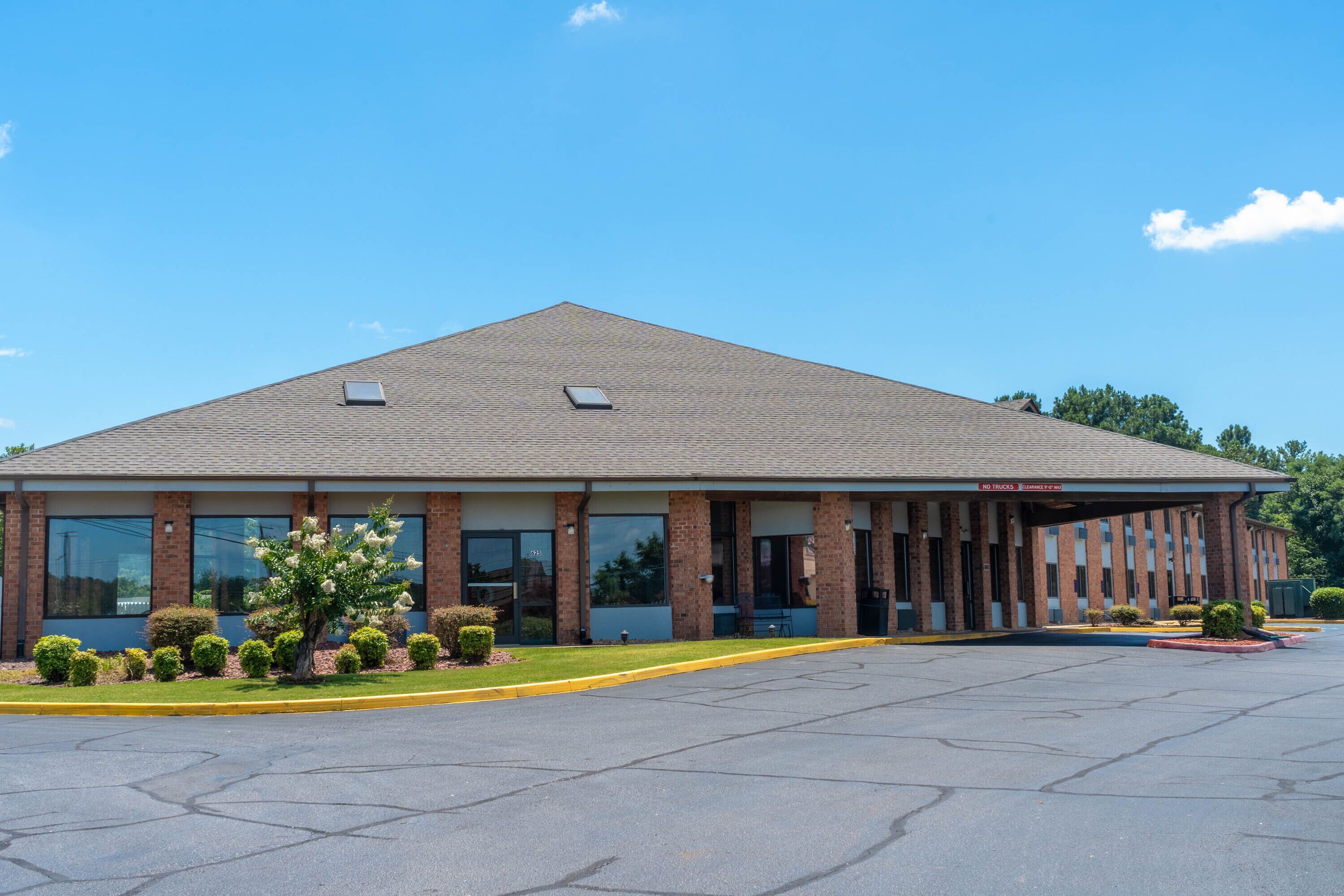 A single-story building with a flat roof, large windows, and a covered entrance area.