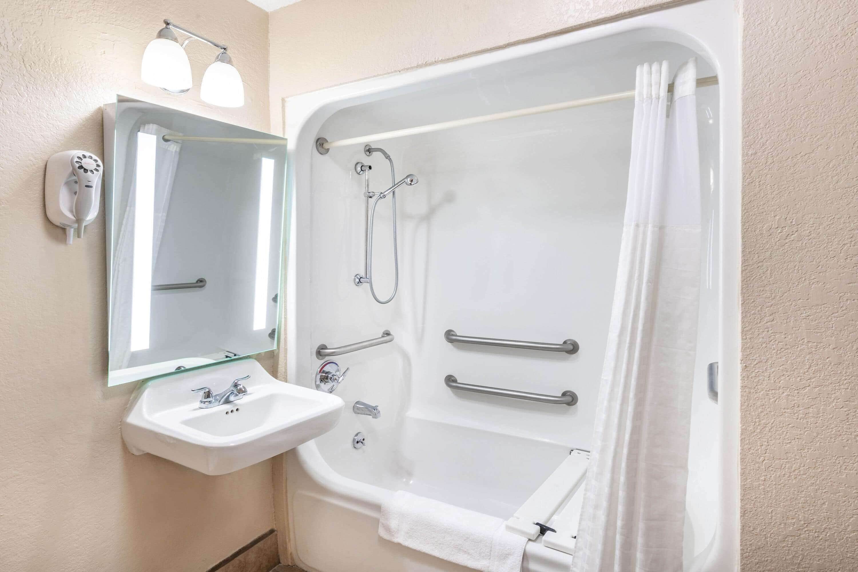 Un baño con una bañera grande, un lavabo, un espejo y un cabezal de ducha manual.