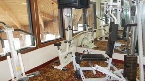 A gym with exercise equipment, a television mounted on the wall, and large windows. - Royalton Inn and Suites Wilmington (Wilmington)