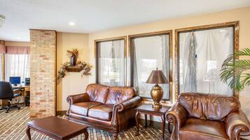 A furnished living room with a leather sofa, a wooden coffee table, and a lamp.