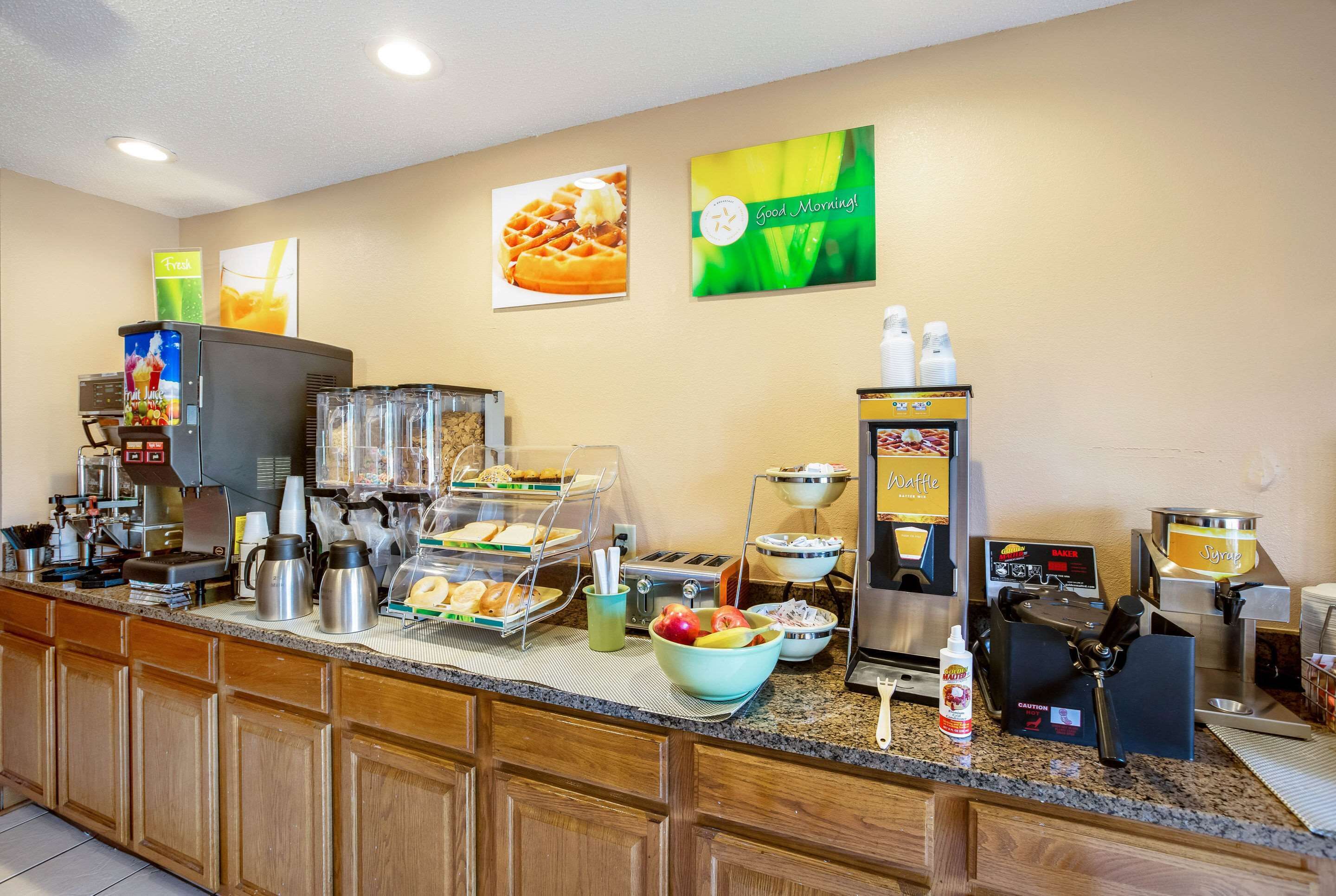 A breakfast bar with coffee machines, waffle makers, and a fruit bowl.