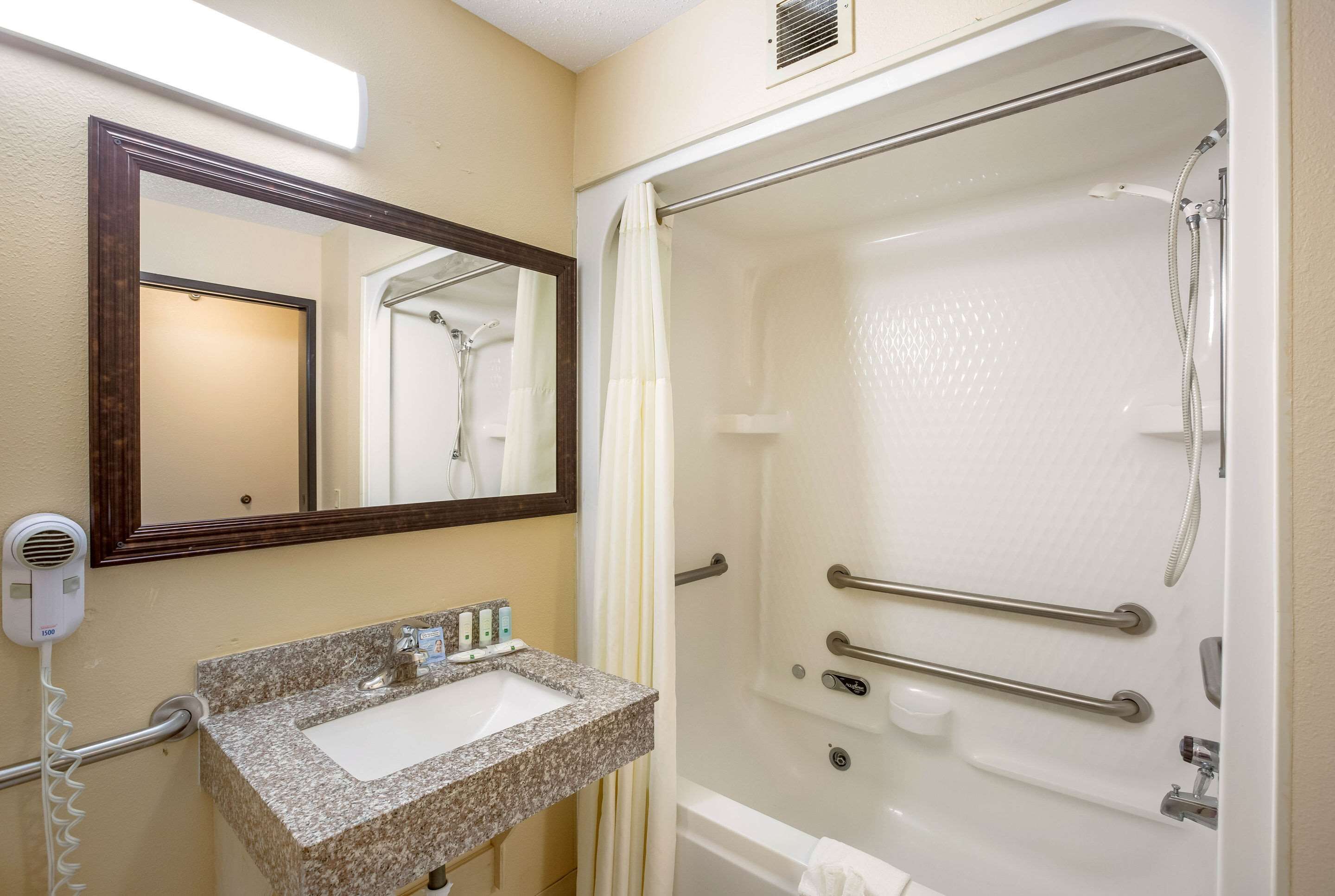 A bathroom with a sink, mirror, and shower.
