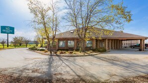 A Quality Inn with a brick building, a covered parking area, and a signboard. - Quality Inn - Storm Lake (Storm Lake)