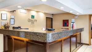 A reception desk with a granite top, framed certificates on the wall, and a fire extinguisher. - Quality Inn - Storm Lake (Storm Lake)