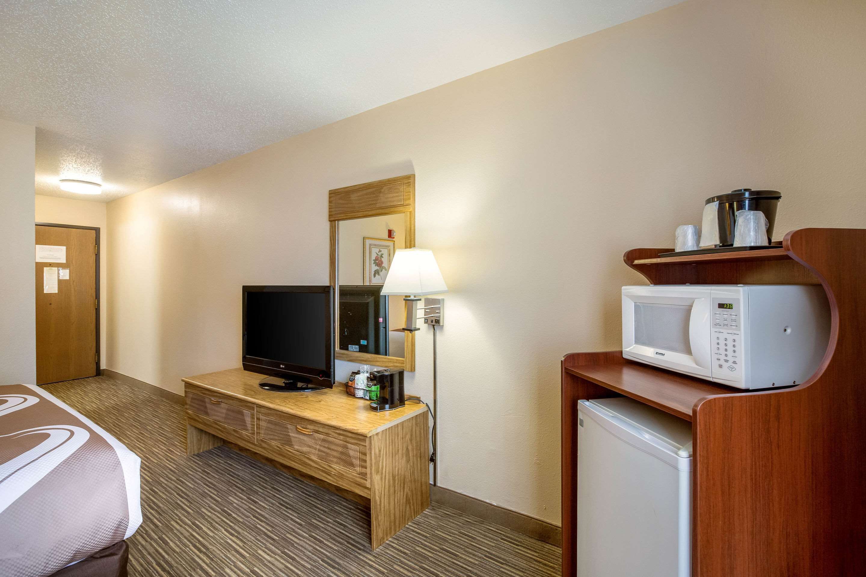 A hotel room with a bed, a TV, a coffee maker, a microwave, and a small refrigerator.