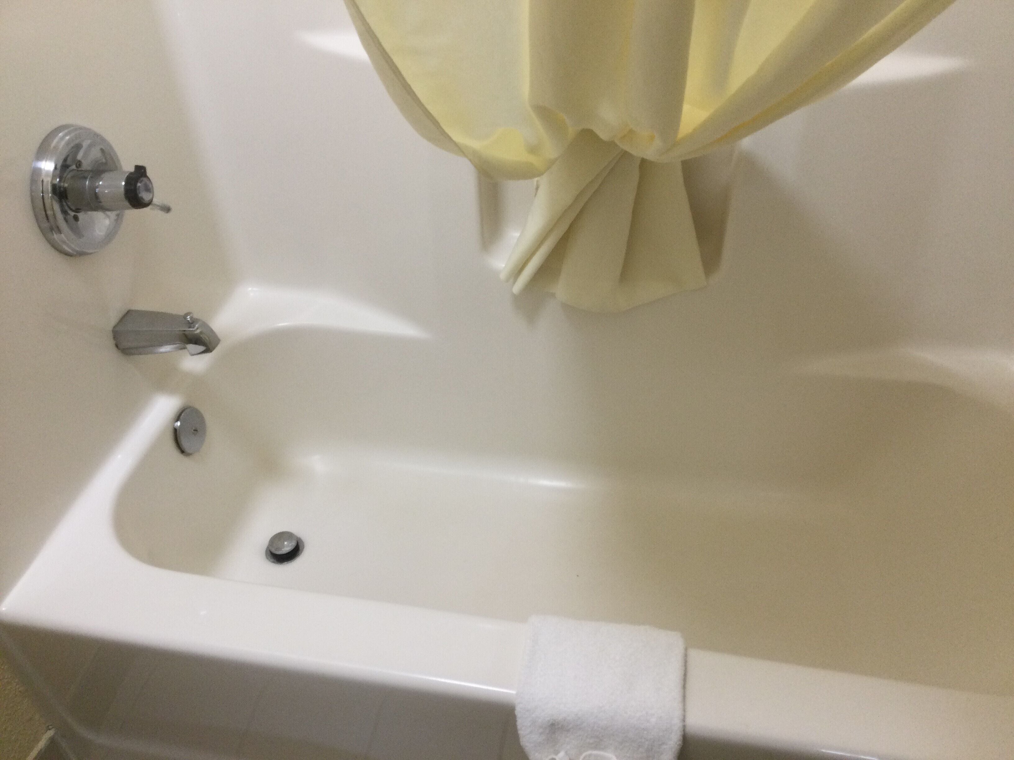 Une baignoire blanche, avec un rideau de douche, un robinet et une serviette accrochée sur le bord.