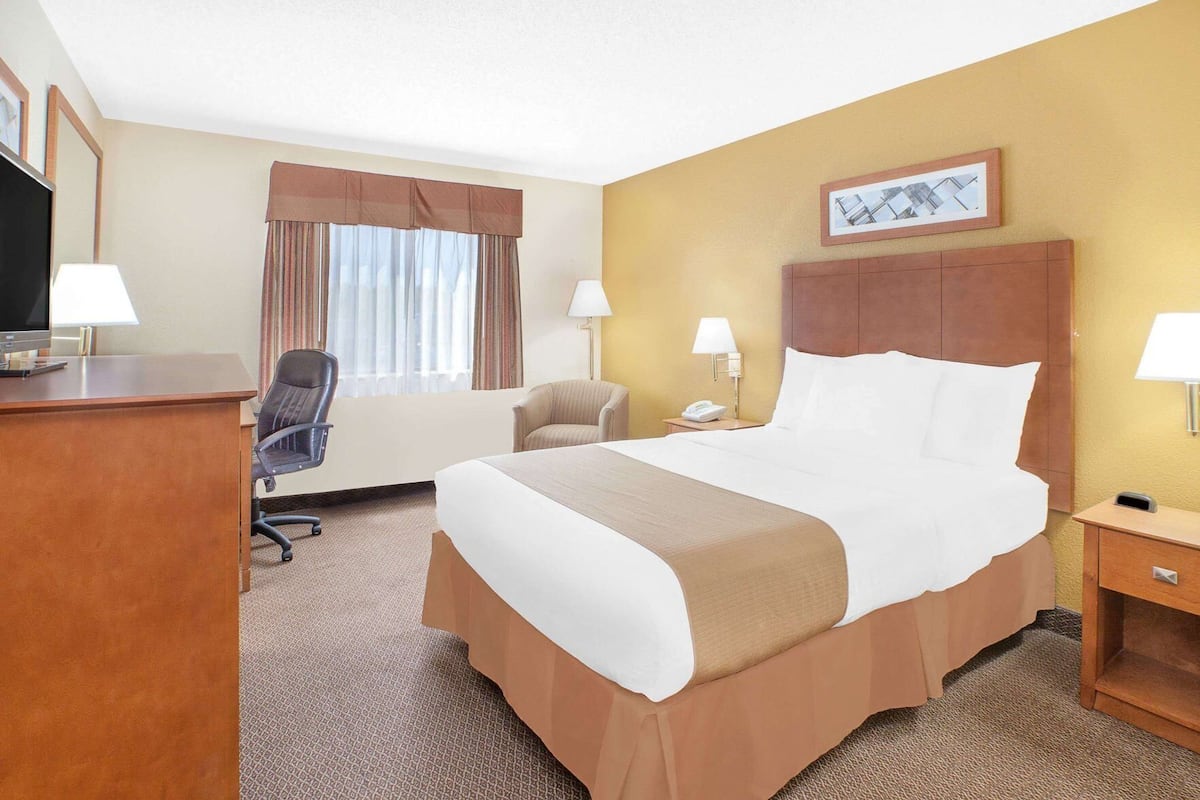 Een hotelkamer met een bed, bureau, stoel en televisie.