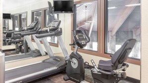 Un gimnasio con cintas de correr, elípticas y una bicicleta estática.