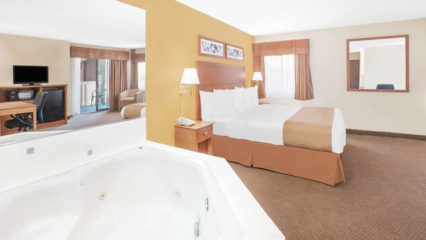 Habitación de hotel con una cama grande, un escritorio con computadora, televisor y bañera.